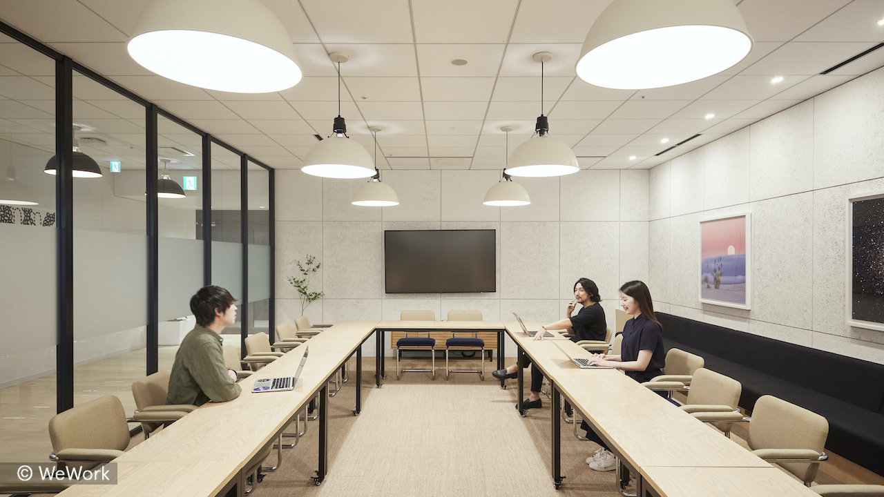 WeWork meeting room with a large table, screen, and seating for team meetings and collaboration.